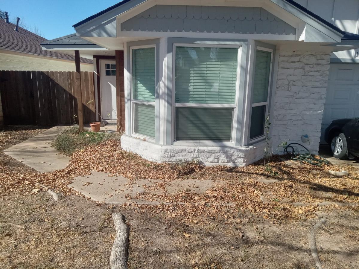 Front flower bed covered in dead leaves before cleanup